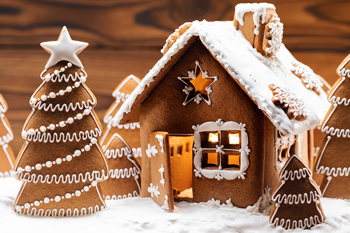 Holiday decorated gingerbread house with gingerbread trees.